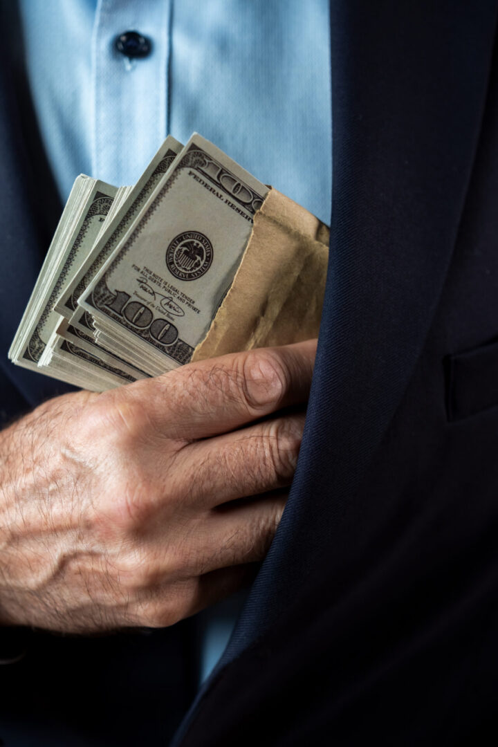 Hand tucking cash into suit jacket pocket