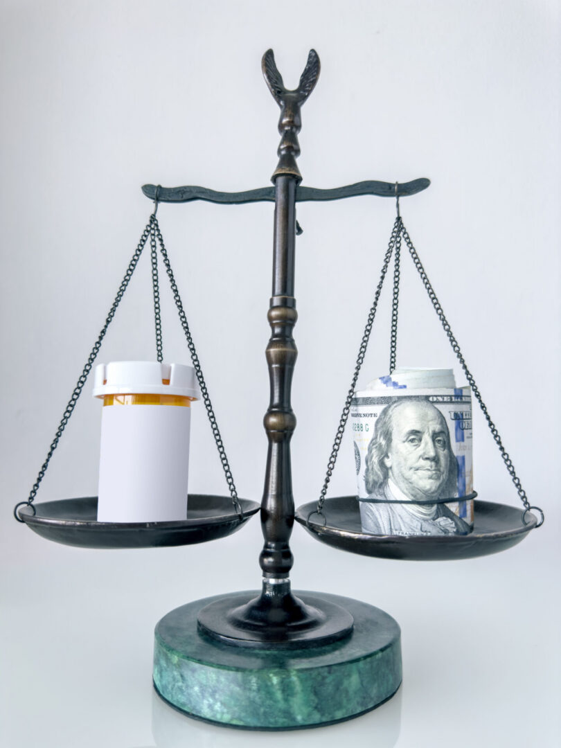 Scales balancing prescription bottle and cash