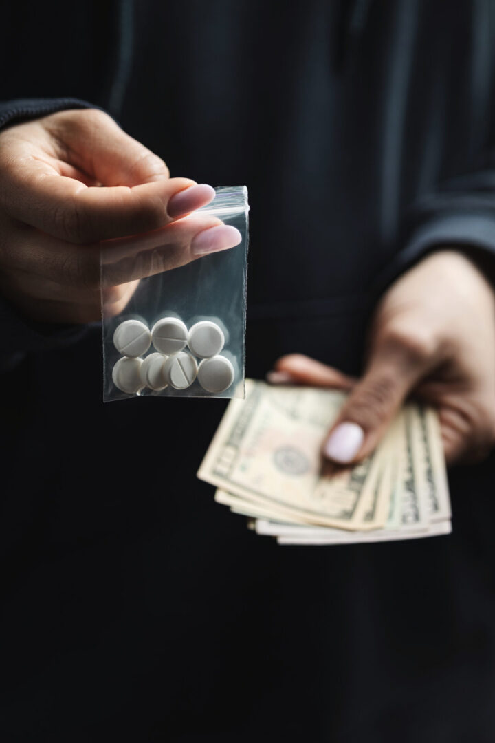Hand passing bag of pills for cash